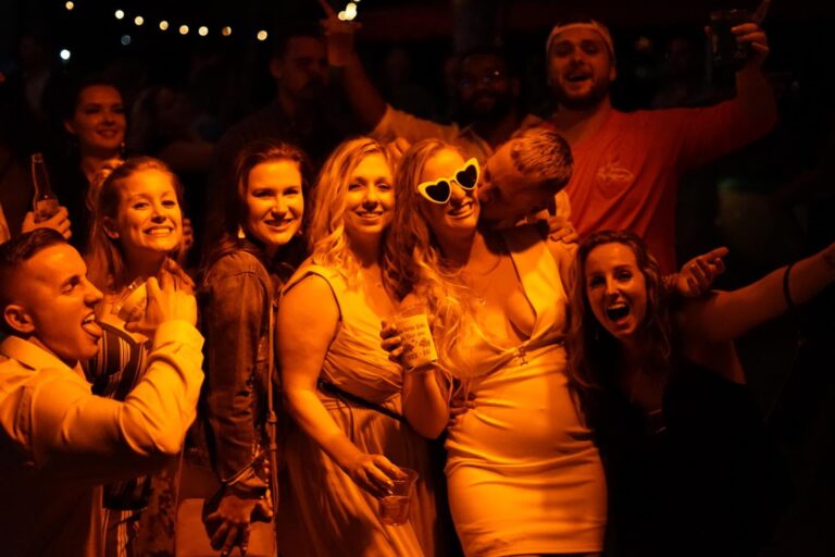 Young adults drinking and partying in a dark room with reddish yellow lighting