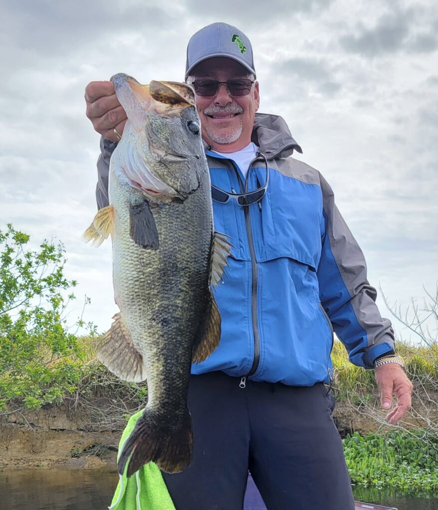 Man smiling and holding his large bass catch
