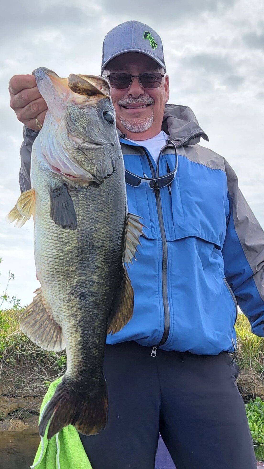 Man smiling and holding his large bass catch